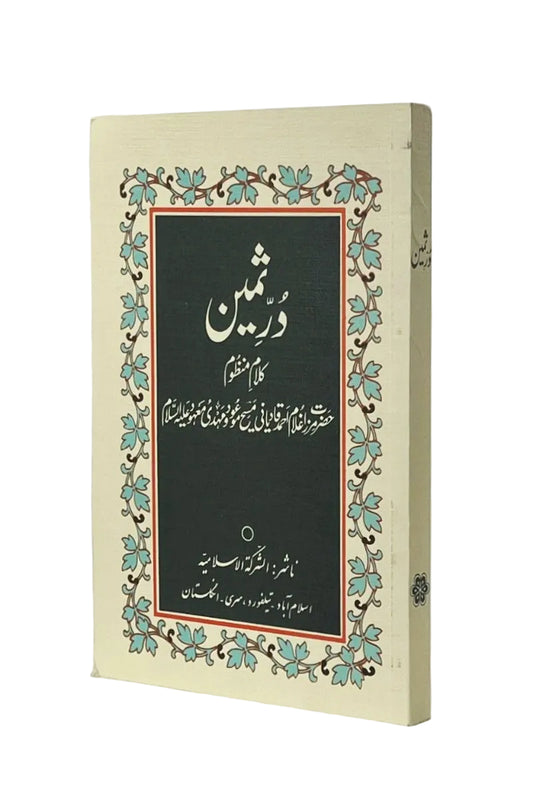 A book with a cream-colored cover featuring a central black panel with white Arabic calligraphy, surrounded by a decorative border of teal leaves and brown vines, photographed on a light gray background.