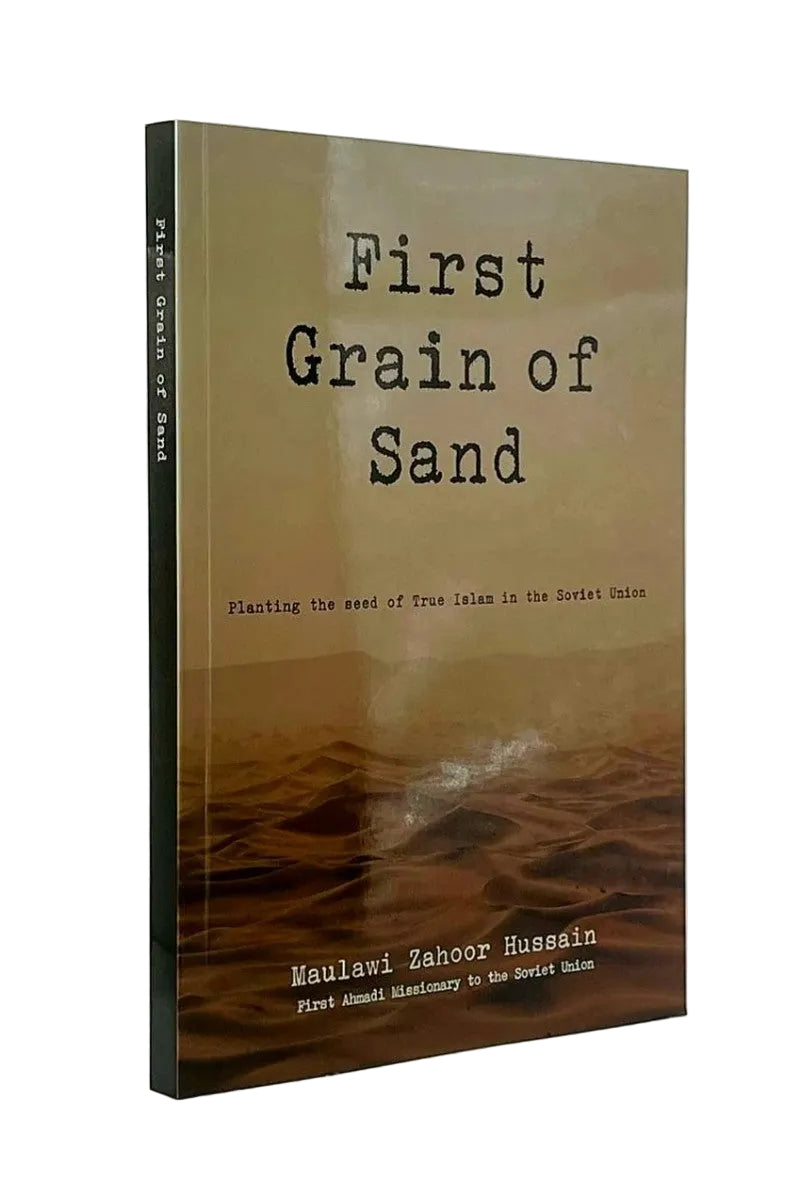 A book titled "First Grain of Sand" by Maulawi Zahir Hussain, standing upright against a plain light background. The cover is tan and brown with a desert landscape image, and the title is printed in a black typewriter-style font.