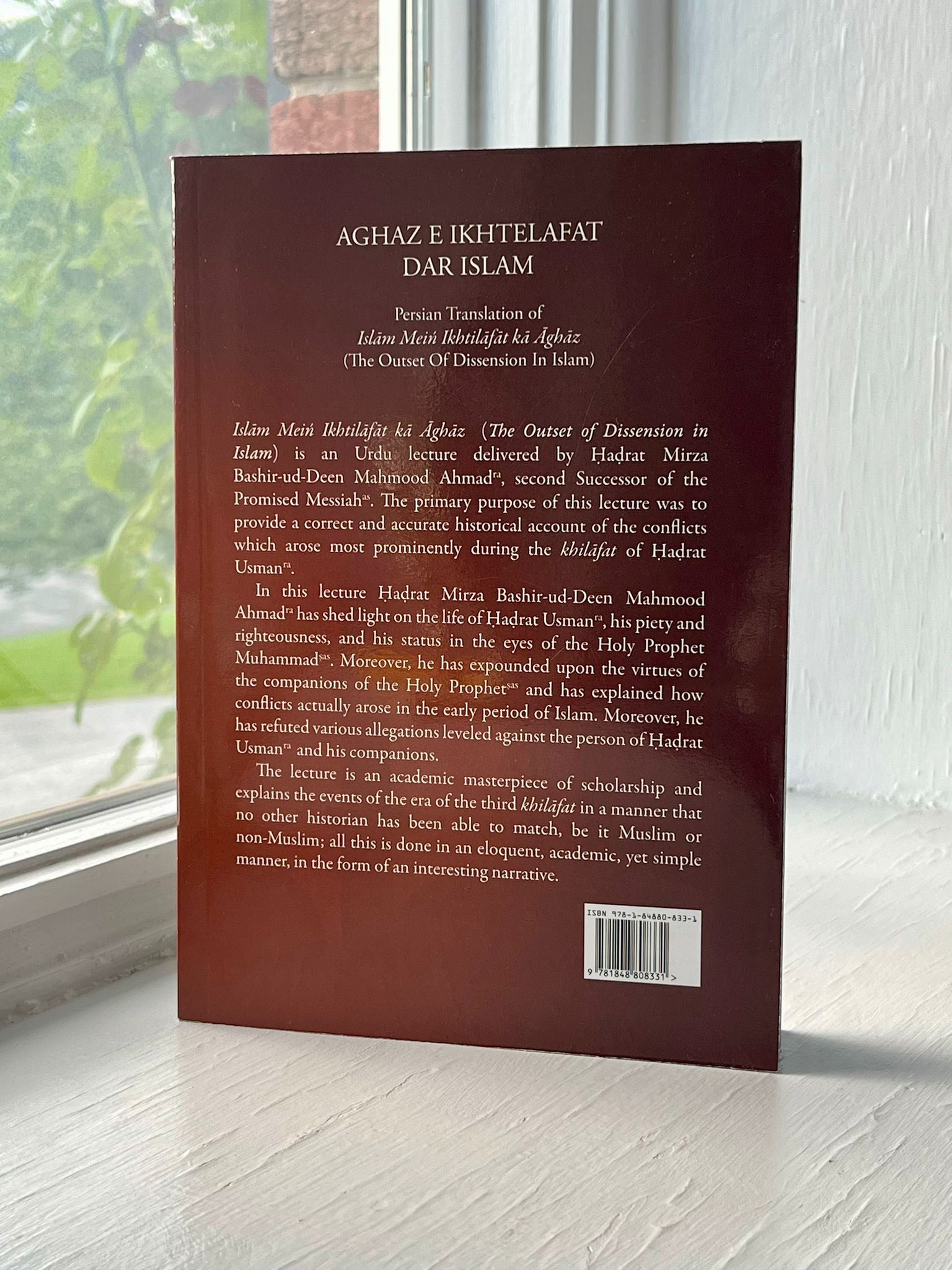 Back cover of a book titled 'Aghaz e Ikhtelafat Dar Islam' with text on a wooden surface.