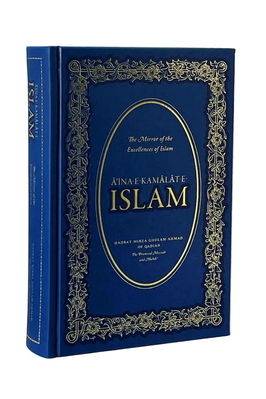 A hardcover book titled 'Ainak Kamalate Islam' in deep blue with ornate gold foil detailing and a gold oval emblem on the front cover, photographed against a neutral light gray background.